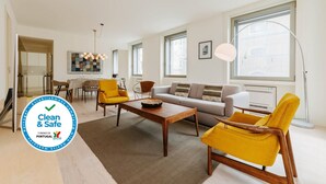 A modern living room with a sofa, two yellow armchairs, a wooden coffee table, and a dining area in the background. - Lady Madonna in Lisboa Ciudad (Lisbon)