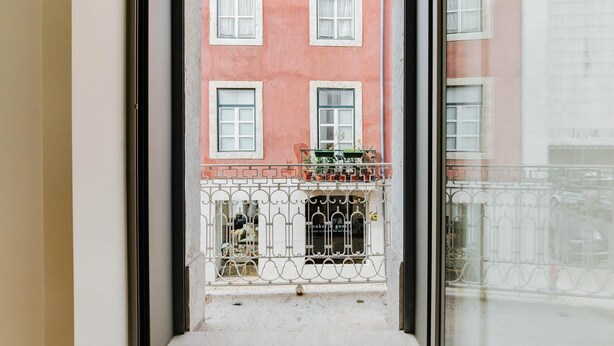 A view from a window overlooking a building with multiple windows and a balcony with a metal railing. - Lady Madonna in Lisboa Ciudad (Lisbon)