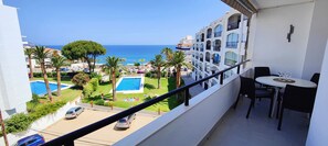 Een balkon met een zwembad, palmbomen en uitzicht op zee.