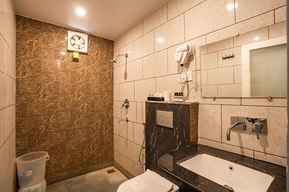 Une salle de bain avec un mur en marbre, un lavabo, un miroir et un sèche-cheveux.