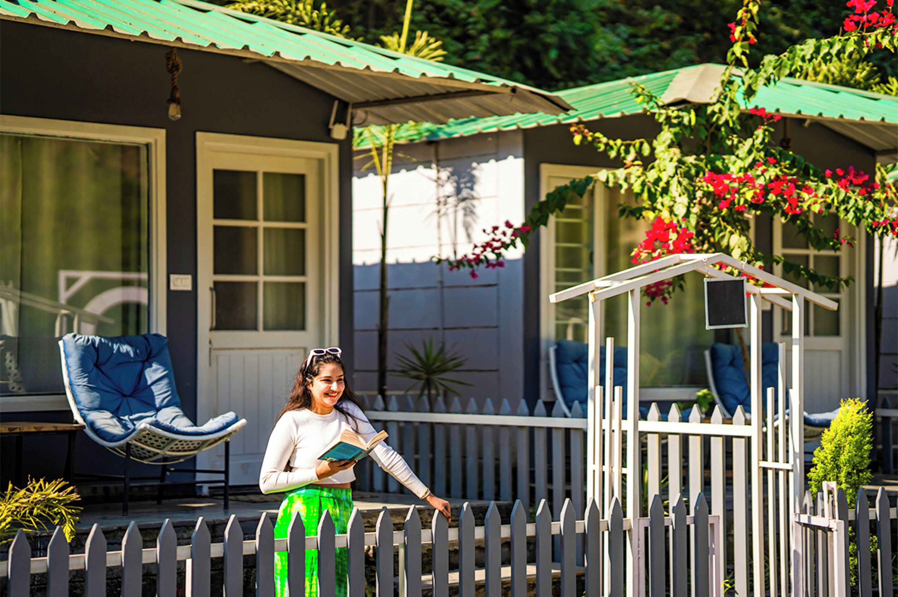 A house with a porch, a white picket fence, and a small gazebo.