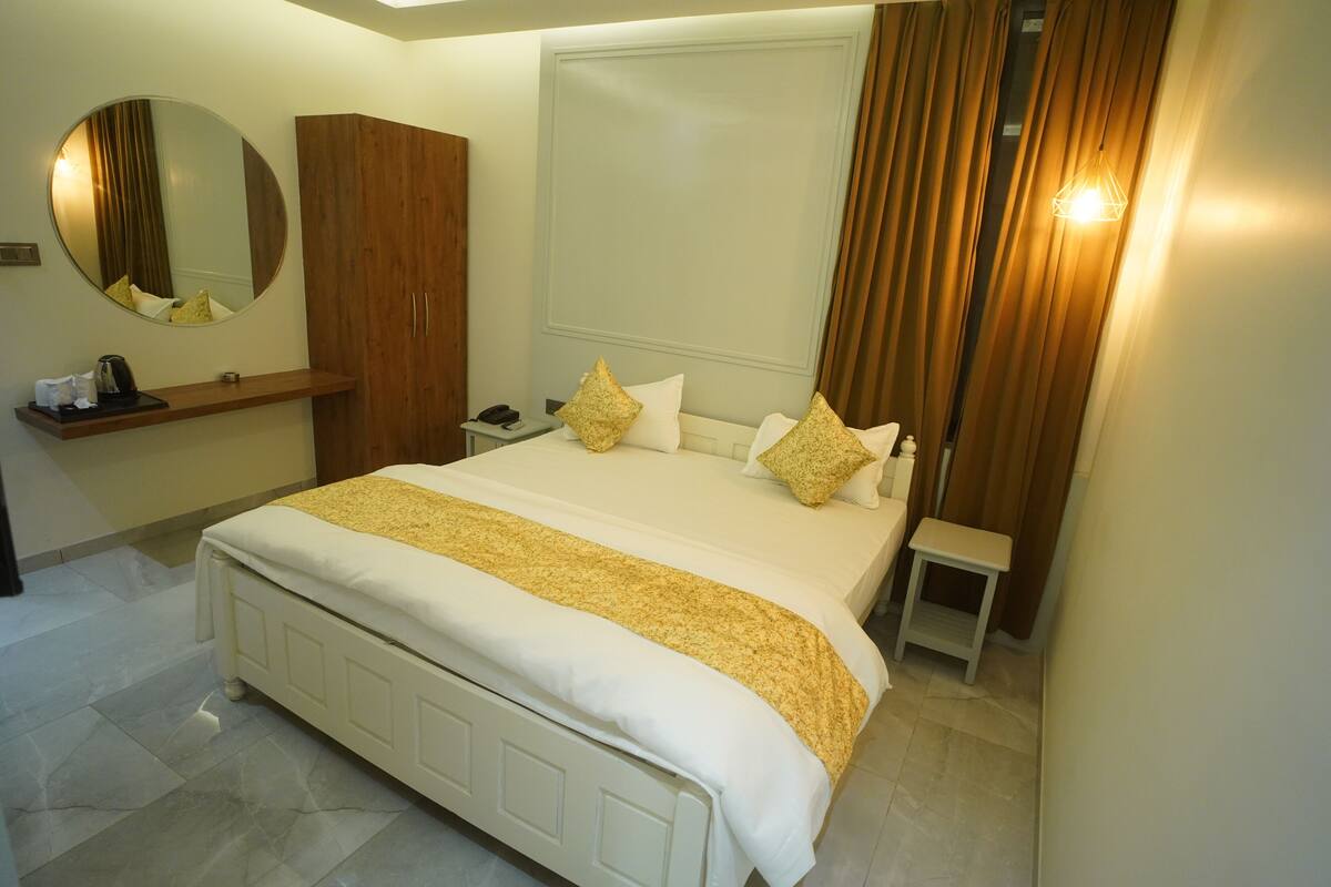 Ein Hotelzimmer mit einem großen Bett, einem Holzschrank, einem Nachttisch, einem Spiegel und einer Pendelleuchte.