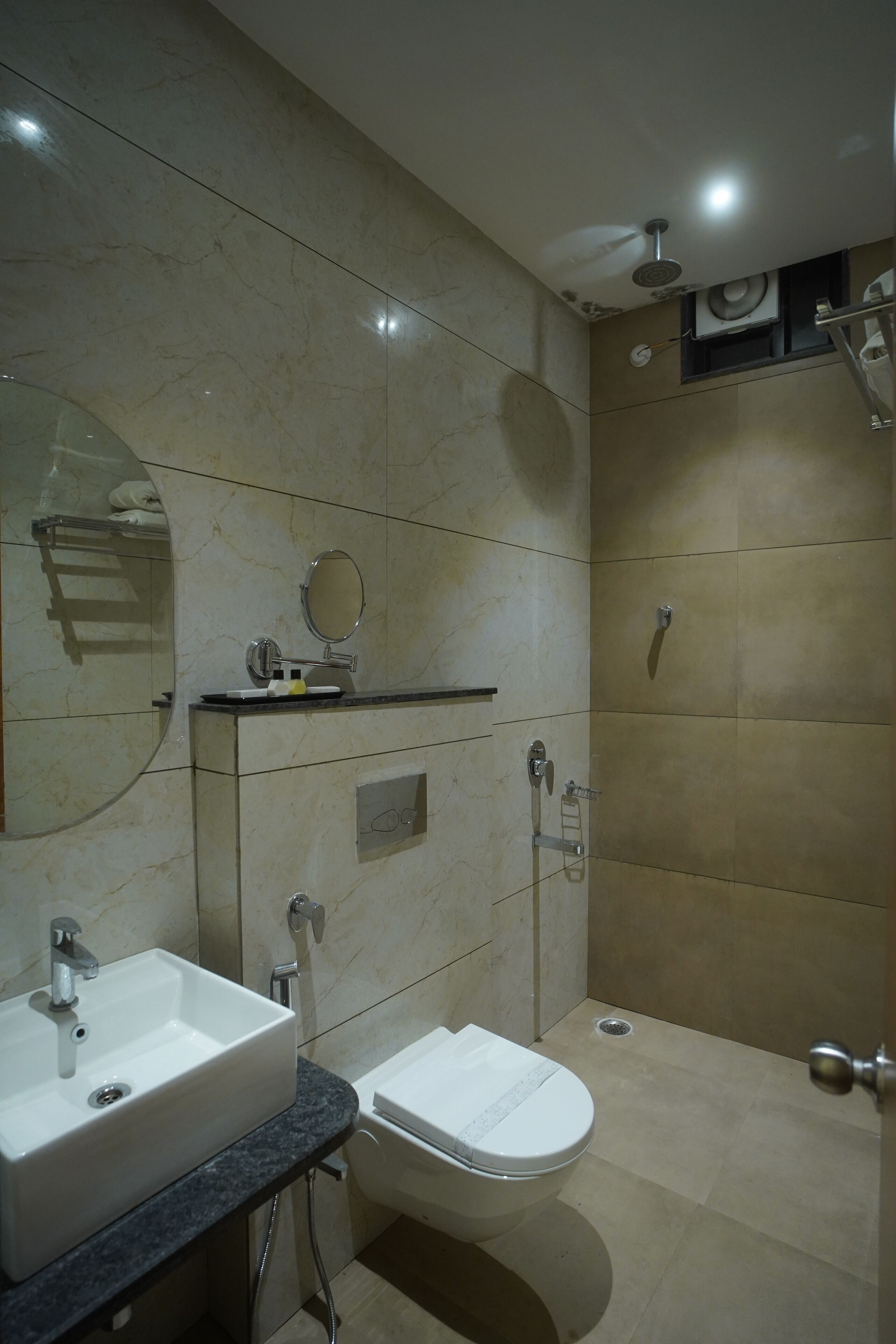 A modern bathroom with a sink, mirror, toilet, and shower.