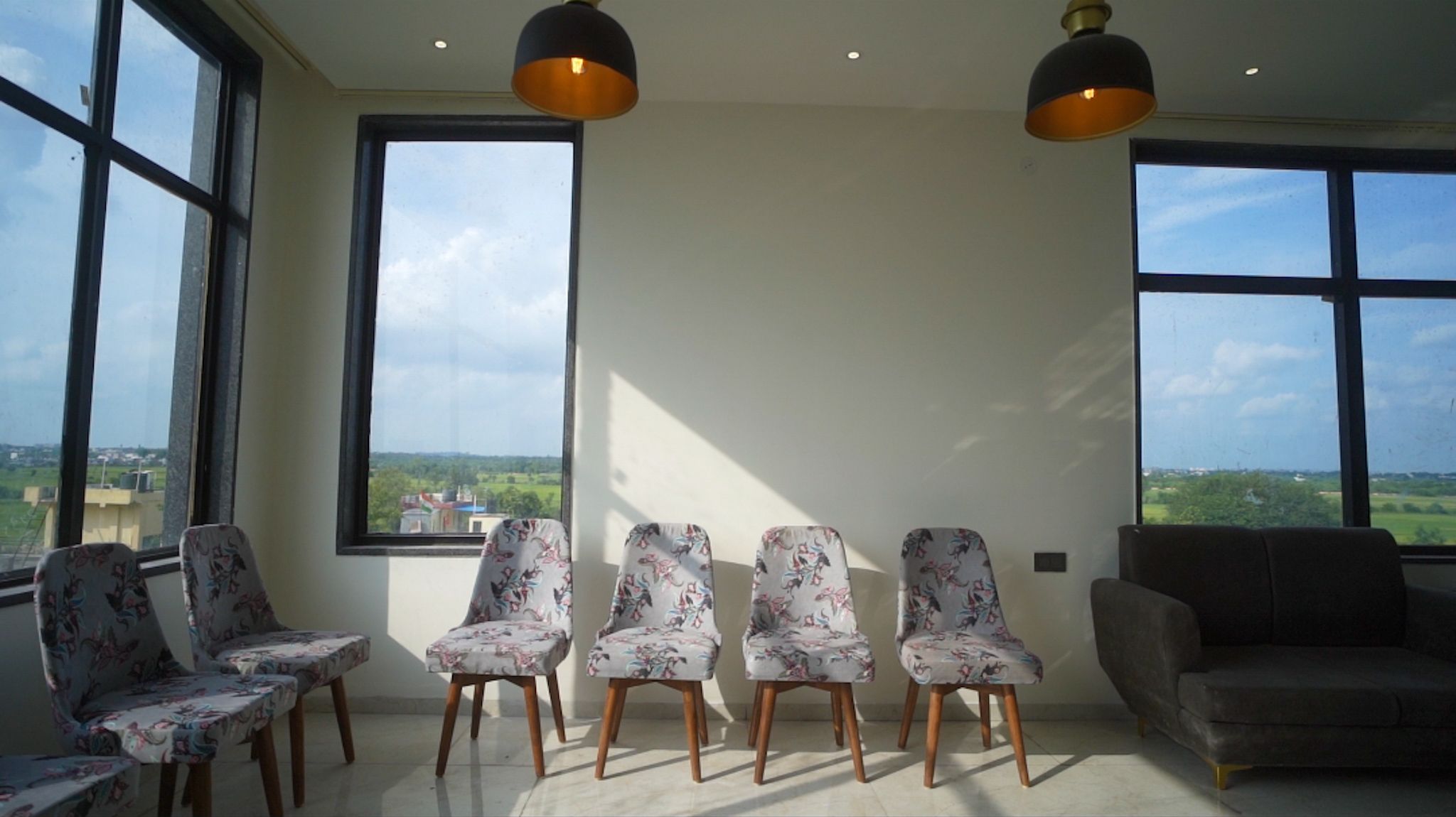 A room with a seating area, large windows, and a view of the countryside.