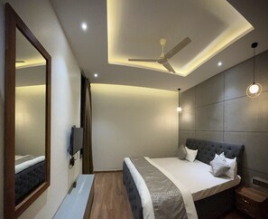 Un dormitorio moderno con una cama grande, ventilador de techo, iluminación empotrada y un espejo.