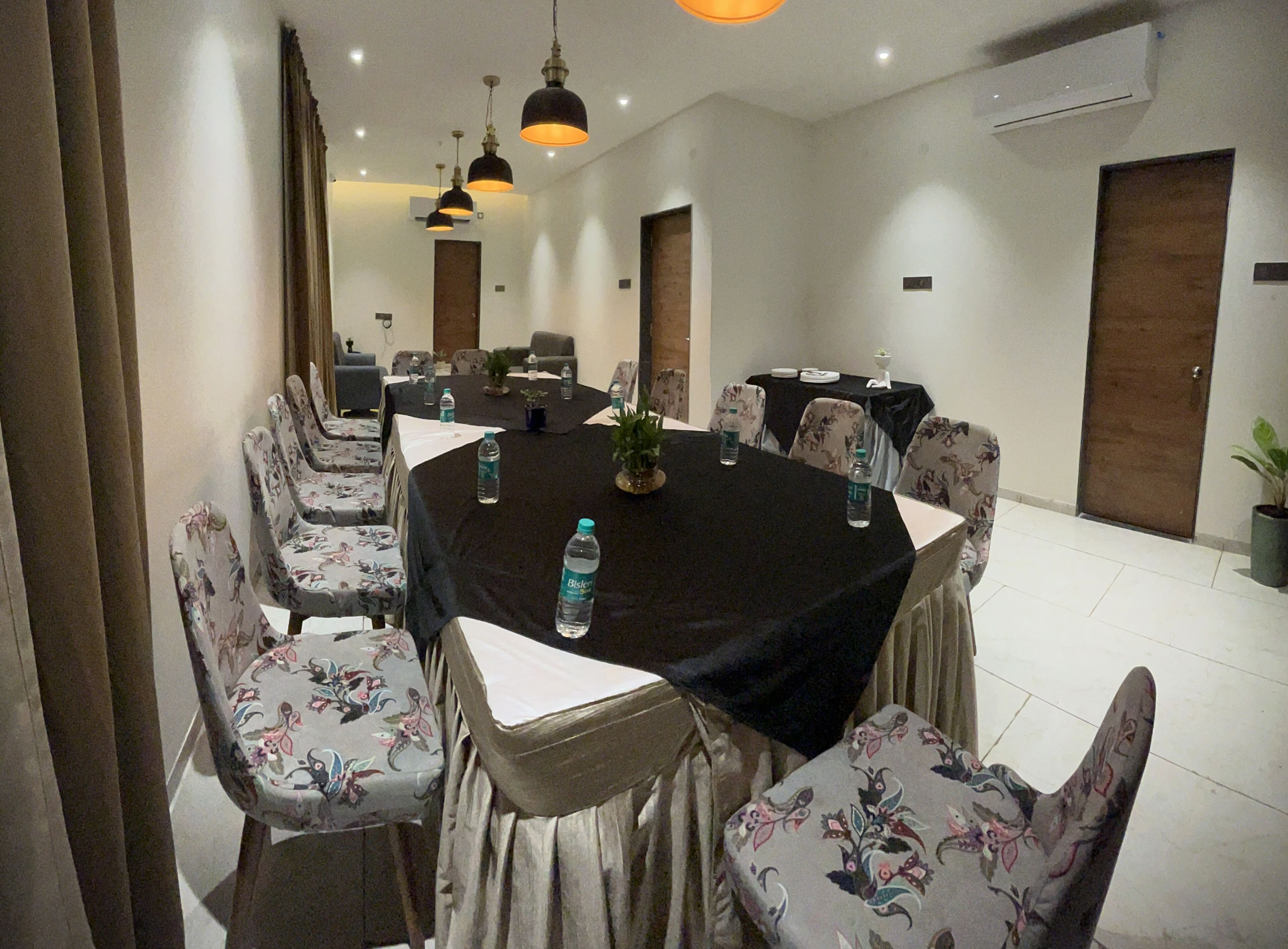 A conference room with a round table, floral-patterned chairs, and water bottles on the table.