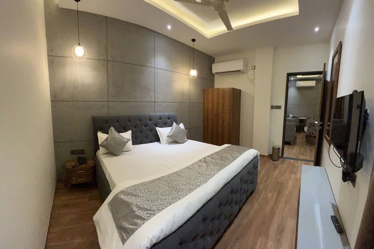 Ein modernes Schlafzimmer mit einem großen Bett, einem Deckenventilator und einem an der Wand befestigten Fernseher.