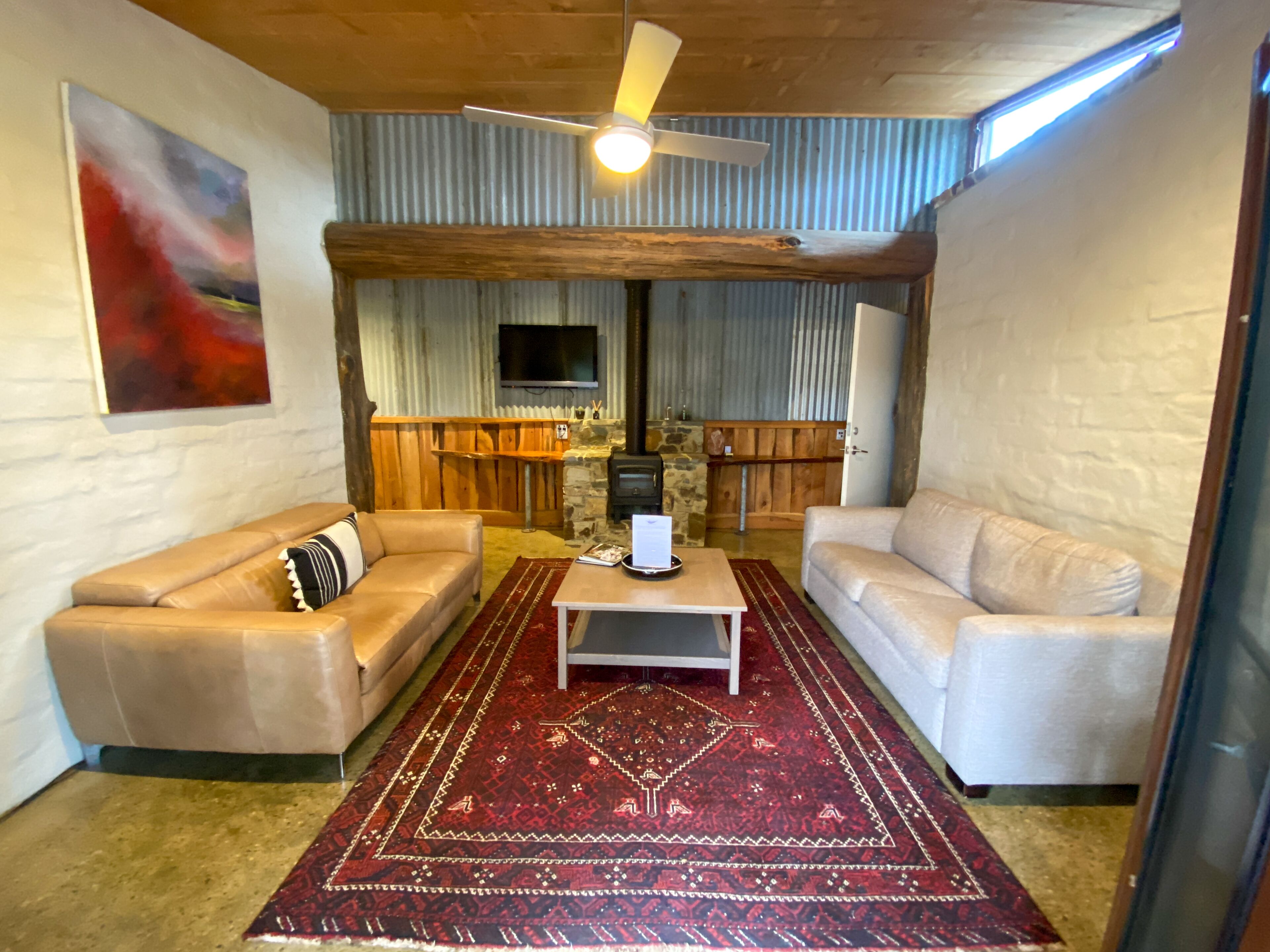 A cozy living room with two sofas, a coffee table, and a red patterned rug.