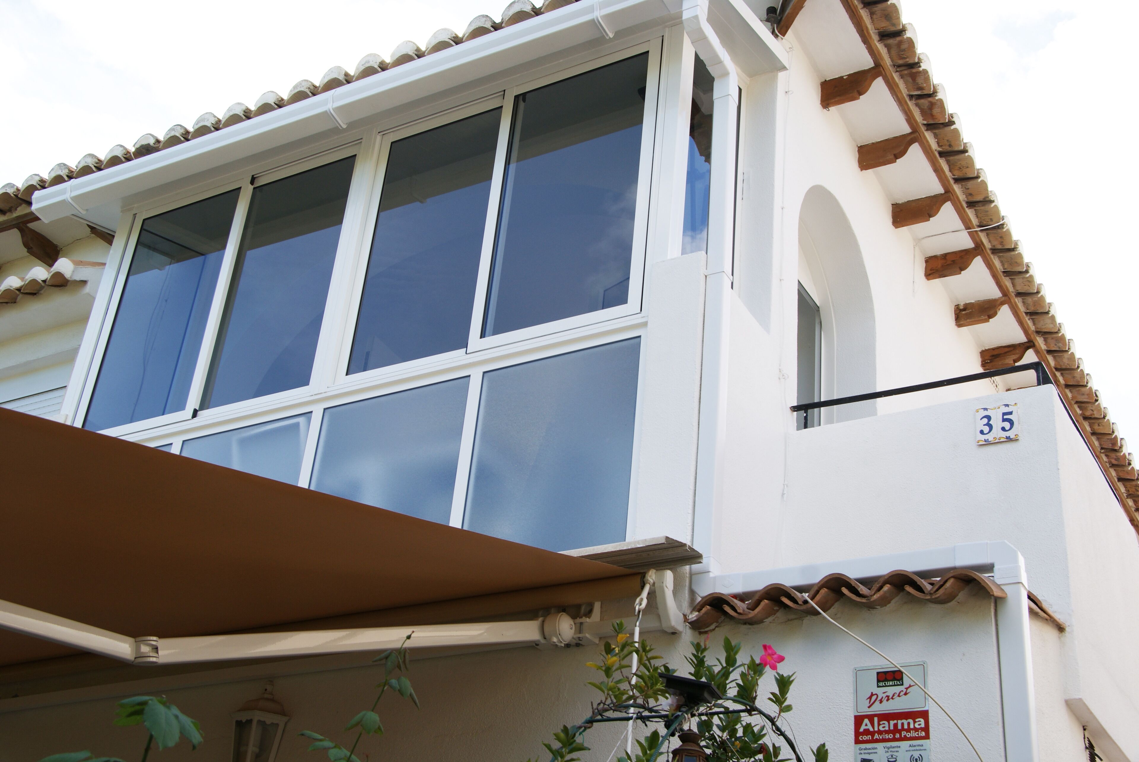 Un edificio con fachada blanca, techo de tejas y un letrero con el número 35.
