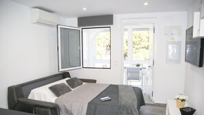 A modern hotel room with a bed, a desk, and a small table with a basket of flowers. - Relax & Comfort in Lago Jardín • Garden Bungalow • Community Pool(35) (LOS BALCONES)
