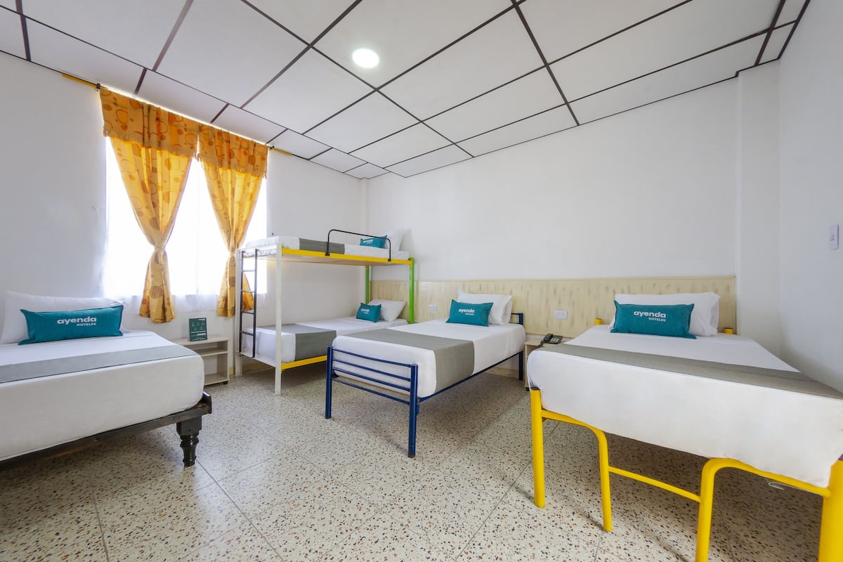 Ein Schlafsaalzimmer mit drei Betten, darunter einem Etagenbett, und einem kleinen Tisch.