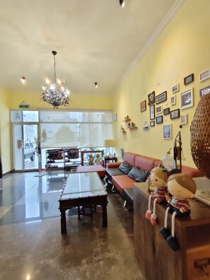 A spacious living area with a chandelier, a sofa, a coffee table, and a wall adorned with framed pictures. - UJU HOUSE (Hualien City)