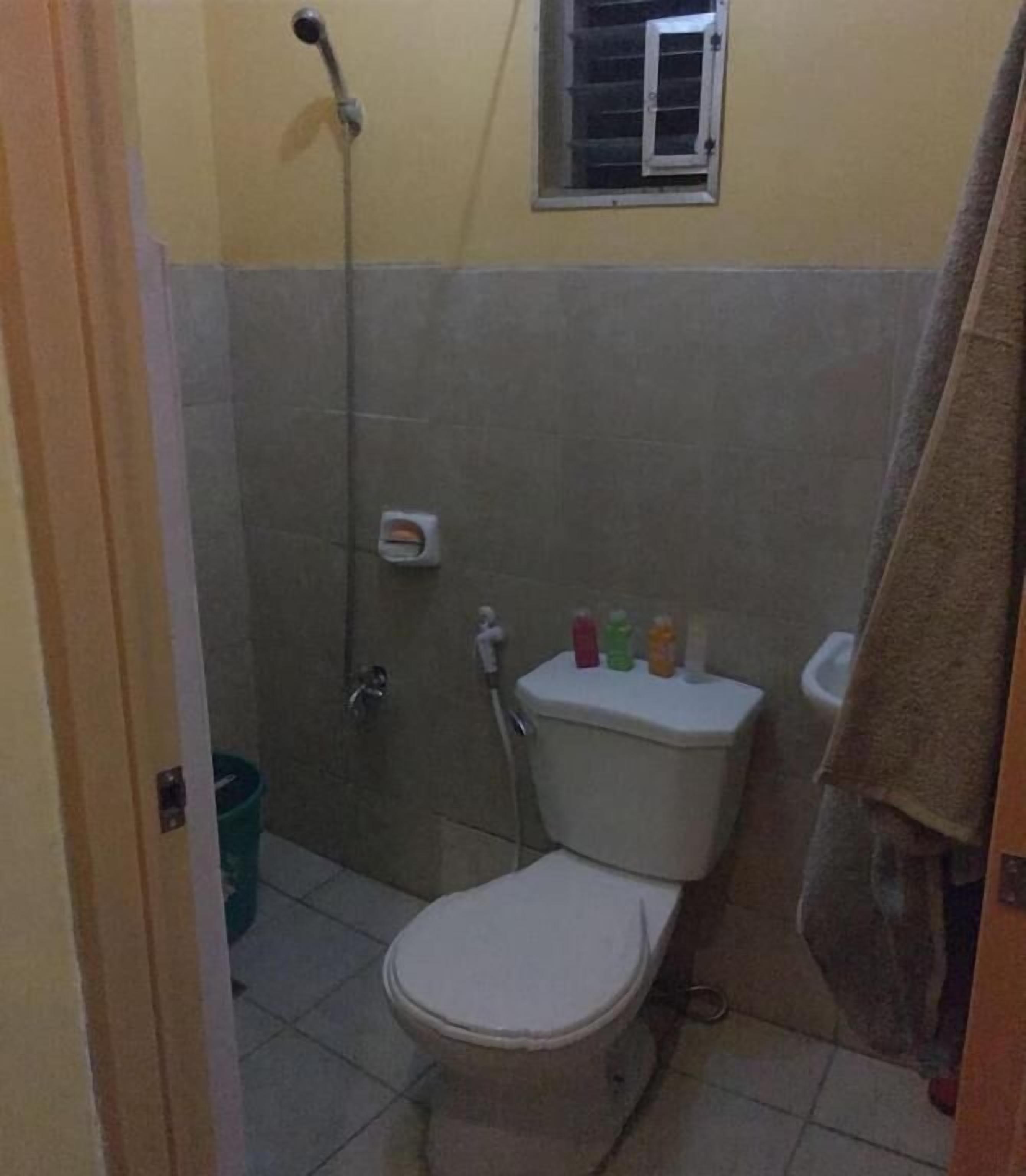 A small bathroom with a toilet, a shower, and a window.
