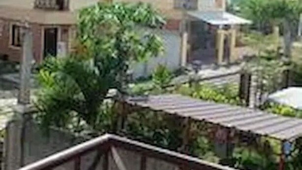 A multi-story building with a flat roof, surrounded by greenery and other structures. - Pines Mansion II House (Butuan)