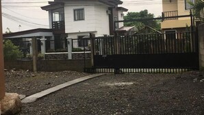 A gated residential area with two houses, one white and one yellow, separated by a black fence. - Pines Mansion II House (Butuan)