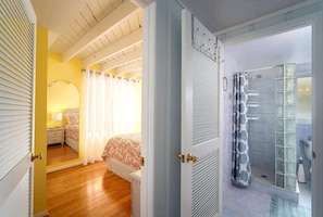 Una camera d'albergo con un letto, un comodino, uno specchio e un box doccia con porte in vetro.