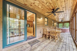 A wooden cabin with a dining area, large windows, and a ceiling fan.