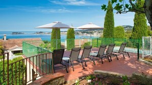 A terrace with outdoor seating and umbrellas overlooking a coastal view. - La Maison de l'Amiral by Interhome (Sanary sur Mer)