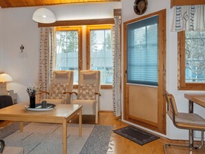 Una habitación con dos sillas, una mesa, una lámpara y un ventanal con persianas.