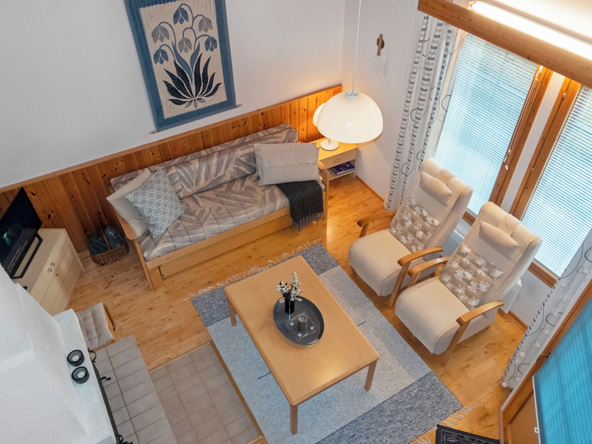 A cozy room with a wooden floor, a sofa, a table with a vase, and a chair.