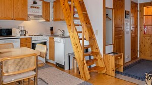 A kitchen with wooden cabinets, a microwave, a stove, and a wooden staircase. - Siulapalkinen a 4 by Interhome (Inari)