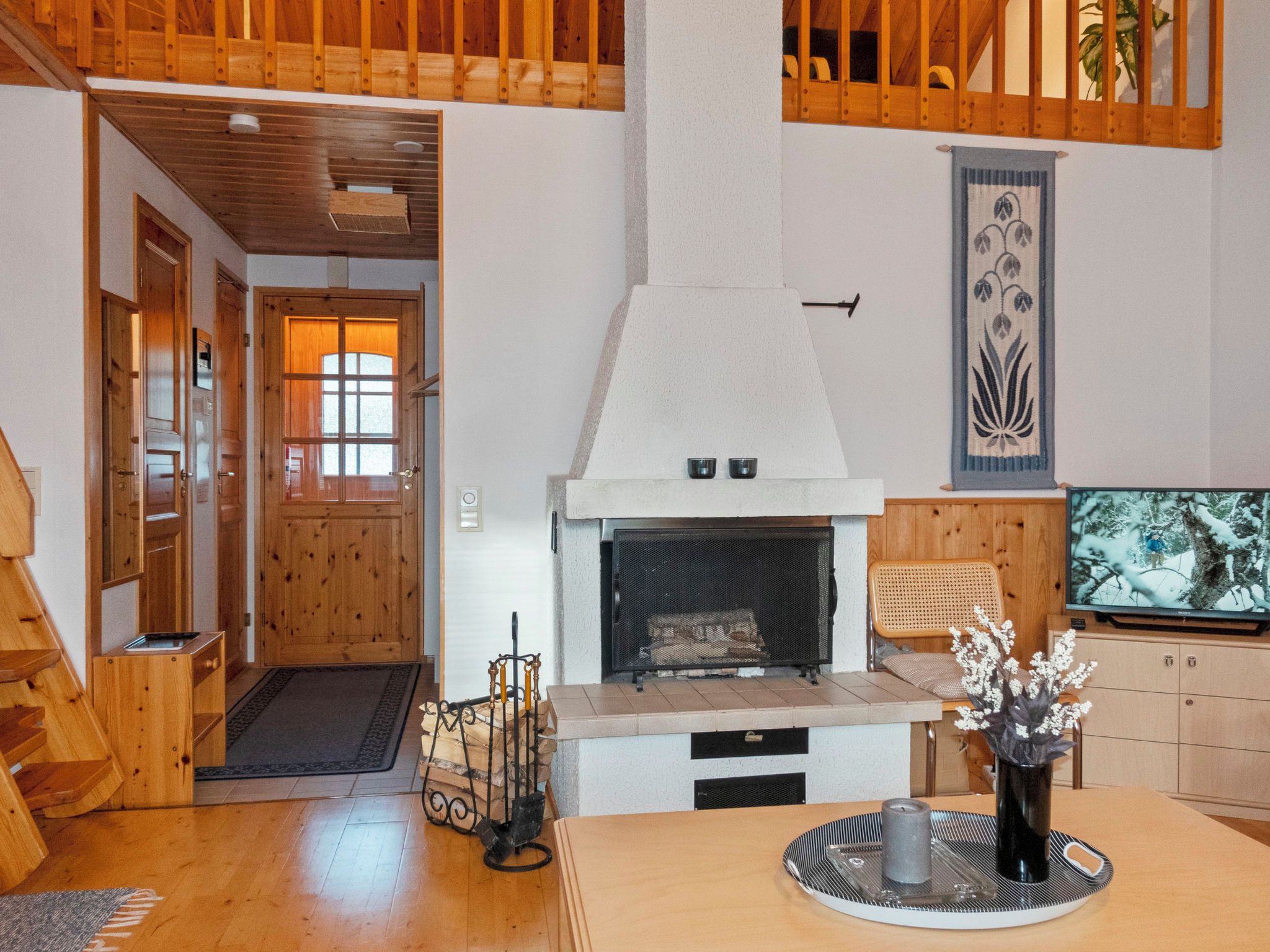Una sala de estar acogedora con chimenea, vigas de madera, televisor y comedor.