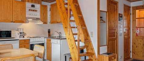 Eine Küche mit Holzausstattung, einem Herd, einer Mikrowelle und einer Holztreppe.