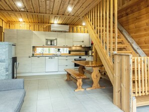 A wooden interior with a kitchen, dining area, and staircase.