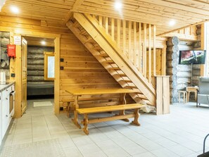 Un intérieur en bois avec un escalier, un banc, un téléviseur et un mur en pierre.