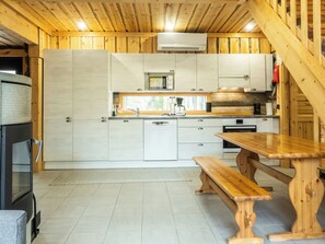 Una cocina moderna con armarios de madera, un microondas integrado y una mesa de comedor de madera con bancos.