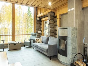 Un interior de cabaña acogedor con chimenea de piedra, un sofá y una silla.