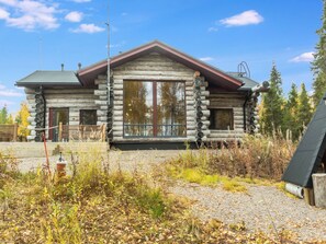 A log cabin with a large window, a chimney, and a wooden deck. - Kojamopirtit by Interhome (Kolari)