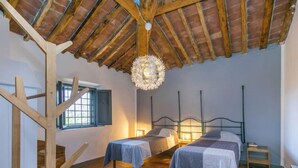 Une chambre rustique avec deux lits, un escalier en bois et un luminaire suspendu.