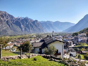 Un village de montagne à l’architecture traditionnelle, doté d’un mur de pierre et offrant une vue sur les montagnes lointaines.
