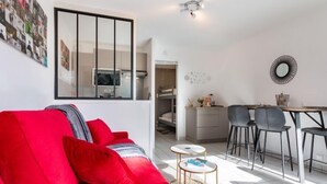 A modern apartment with a red sofa, a dining area with a table and chairs, a kitchen, and a large mirror on the wall. - Apartment Océan by Interhome (Carnac)