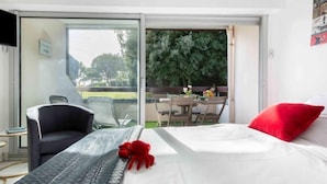 A hotel room with a bed, a desk, a chair, and a balcony with a table and chairs. - Apartment Océan by Interhome (Carnac)