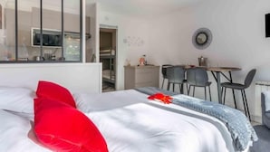 A modern bedroom with a large bed, a dining area, and a kitchen visible through an open door. - Apartment Océan by Interhome (Carnac)