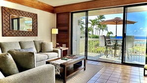 Un salon comprenant un canapé, une table basse et donnant sur un balcon aménagé avec du mobilier d’extérieur et une piscine.