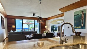 Une cuisine moderne dotée d’un grand îlot central, un coin repas avec vue et un salon comprenant un canapé et une table.