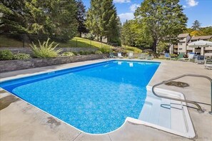 Une piscine rectangulaire à l’eau d’un bleu limpide, entourée d’une terrasse en béton.