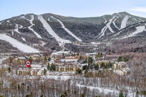 Une station de ski comprenant plusieurs bâtiments, un télésiège et des montagnes enneigées.
