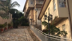 Un sentiero lastricato conduce a un edificio con balconi e piante in vaso.