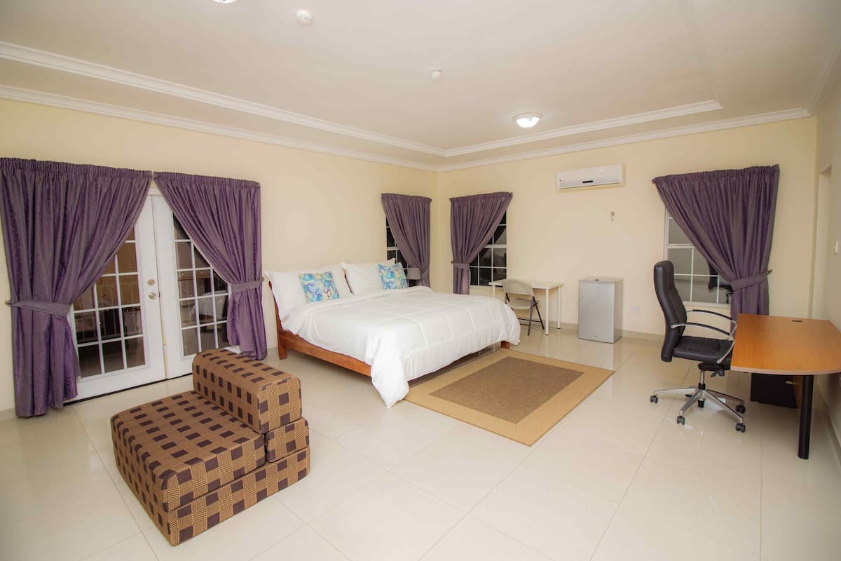 A bedroom with a bed, a desk, a chair, a sofa, and a small table.