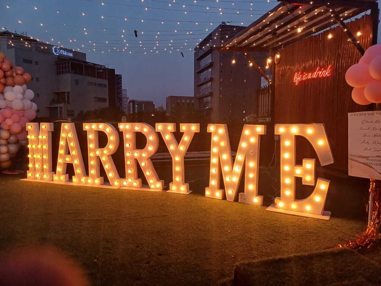 Letras iluminadas que deletrean "HARRYME", con un letrero de neón en el fondo.