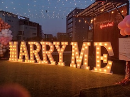 Letras iluminadas que deletrean "HARRYME", con un letrero de neón en el fondo.