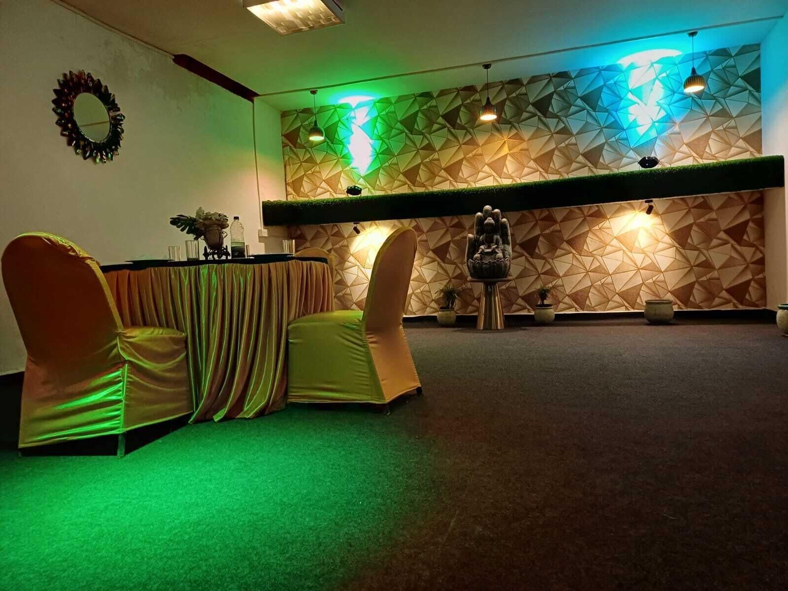 Un salón de conferencias con un muro de diseño geométrico, una estatua de Buda y una mesa con sillas.