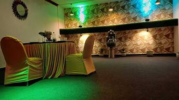 Un salón de conferencias con un muro de diseño geométrico, una estatua de Buda y una mesa con sillas.