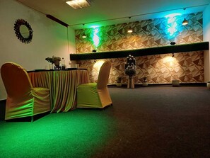 A conference room with a geometric patterned wall, a Buddha statue, and a table with chairs. - Live Inn Hotel sector 45 (Gurugram)