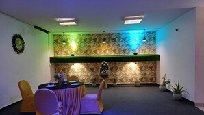 A conference room with a geometric patterned wall, a round table with chairs, and a small Buddha statue. - Live Inn Hotel sector 45 (Gurugram)