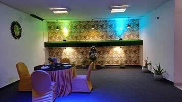 A conference room with a geometric patterned wall, a round table with chairs, and a small Buddha statue.